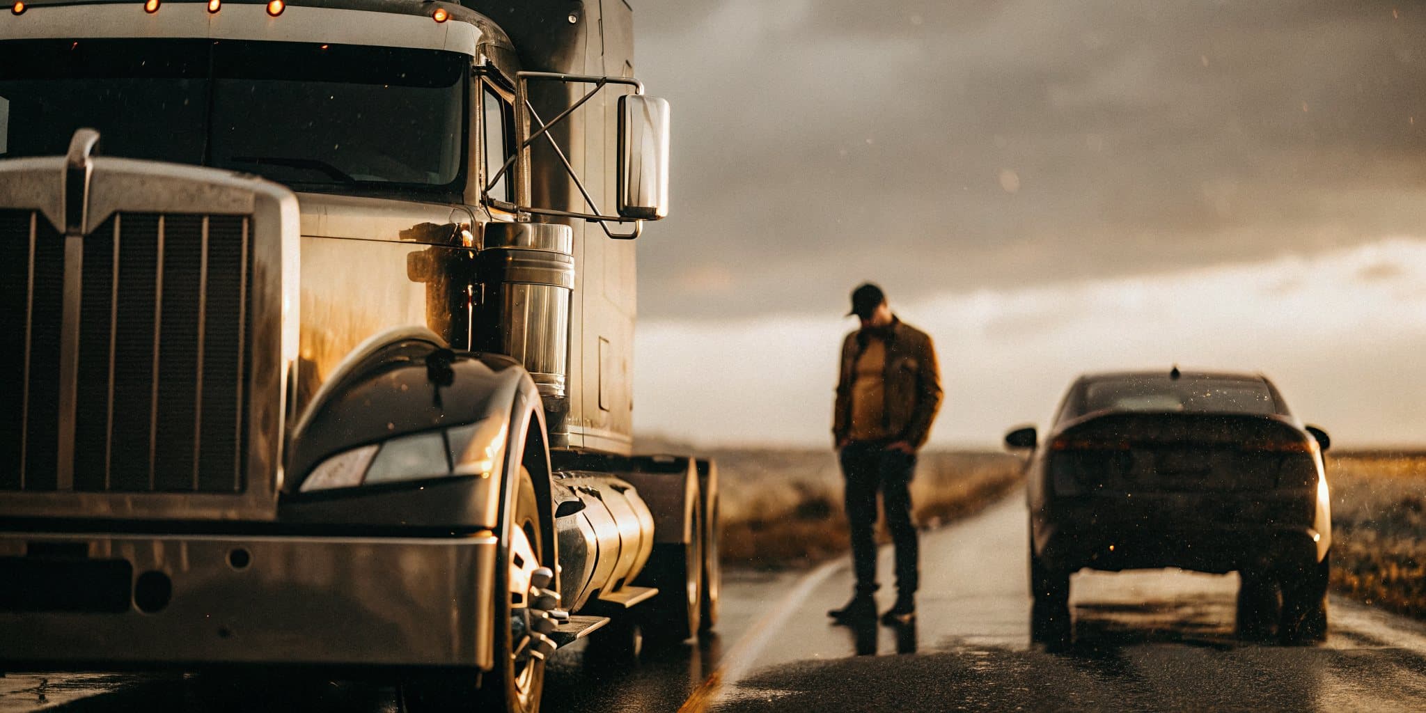 A semi-truck and a car stopped on a highway shoulder after a collision
